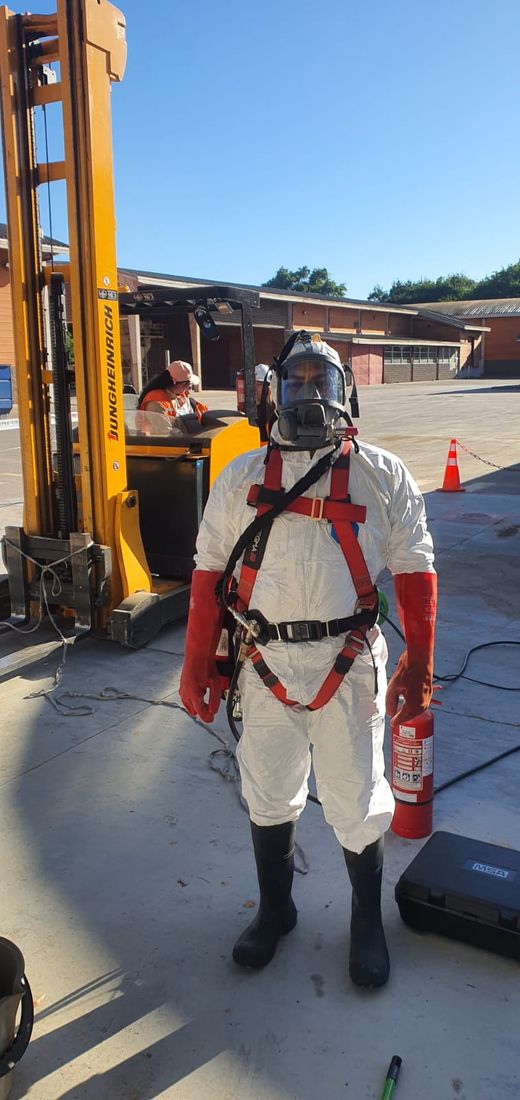 Técnico con equipo de protección personal completo: traje, arnés y respirador