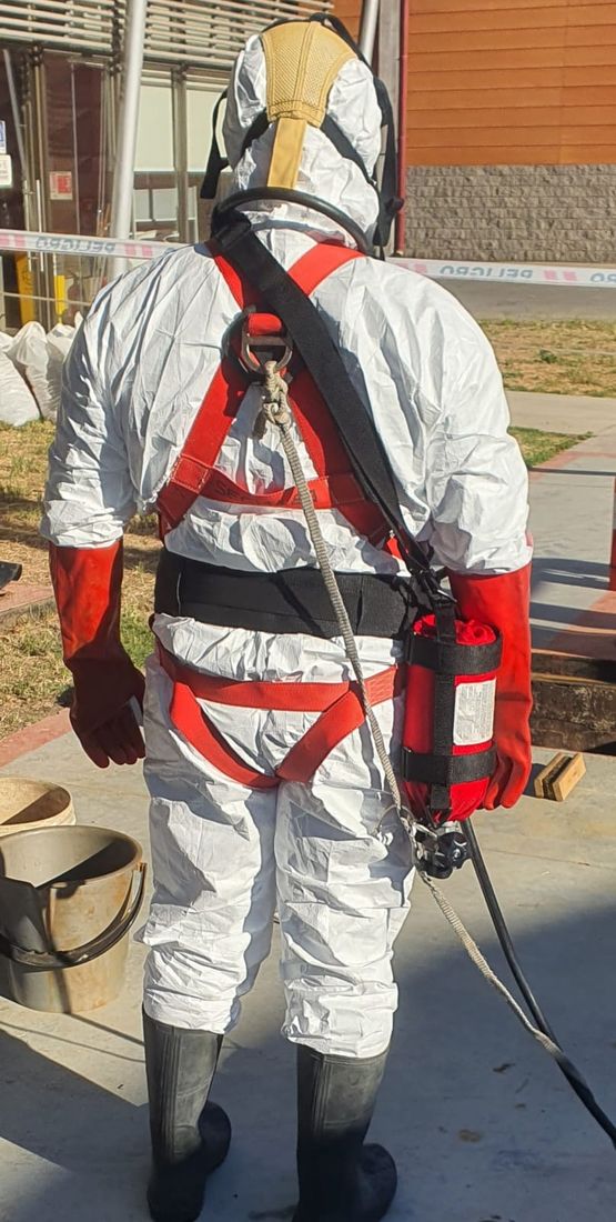 Técnico con arnés de seguridad y equipo de respiración autónoma en faena